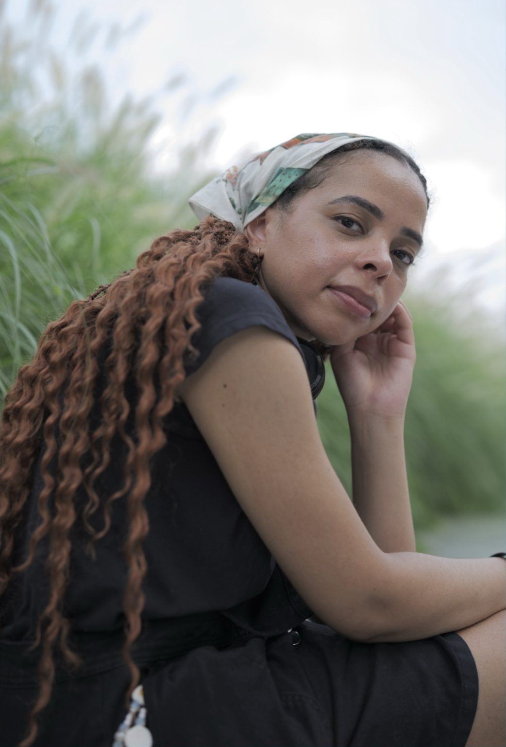 A picture of a Black woman resting her hand on her palm while sitting down